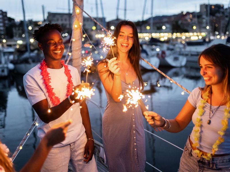 Group of people having fun and celebrating with sparklers on a boat