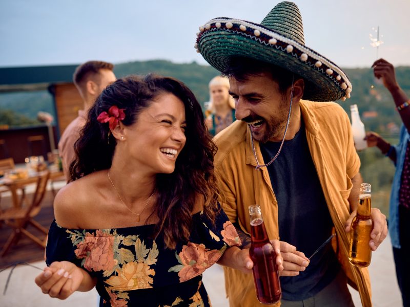 Happy couple having fun while dancing on a party with friends on a patio.