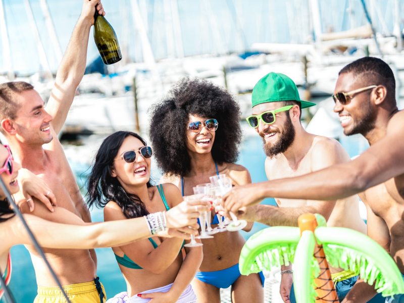 Trendy friends having fun toasting champagne wine at sailboat party